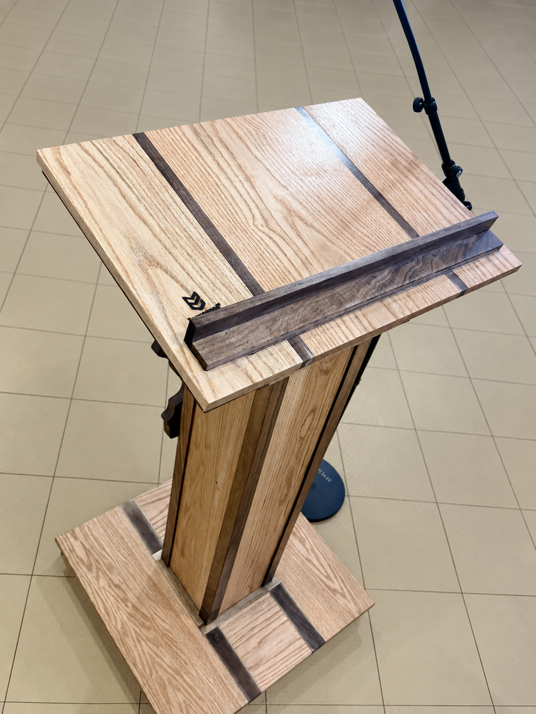 Top view showing the podium’s angled hardwood presentation surface, contrasting inlays and document retention ledge